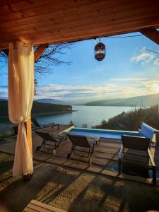 Un patio con sillas y una piscina y vista al agua. en Moon Lake Bicaz - Casa Oia, en Buhalniţa