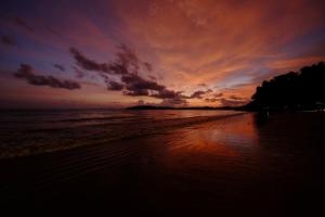 a sunset on a beach with the ocean at Base Party Hostel in Ao Nang Beach