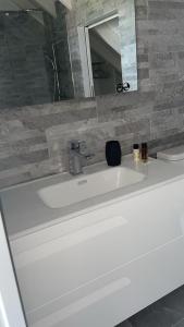 a white sink in a bathroom with a mirror at Villa Outaouais T4 in Bielle +8 photos