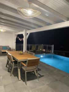 a dining room with a table and a swimming pool at Villa Outaouais T4 in Bielle