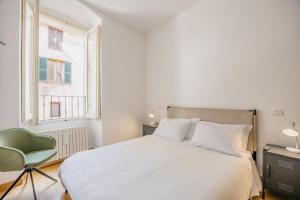 een slaapkamer met een wit bed en een groene stoel bij BHR - La Finestra su Spoleto in Spoleto
