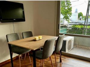a dining room table with chairs and a flat screen tv at Tempo Apart in La Plata