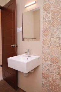 a bathroom with a white sink and a mirror at Hotel Sahaya Arasi in Kovakulam
