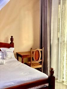 Un dormitorio con una cama, una silla y un escritorio. en Nilevic Guest House Entebbe, en Entebbe