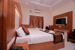a hotel room with a bed and a television at Hotel Sahaya Arasi in Kanyakumari