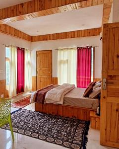 a bedroom with a large bed with red curtains at woodstock villa & cafe in Jibhi