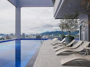 a row of lounge chairs sitting next to a swimming pool at Central Georgetown Studio with Nespresso Machine in George Town