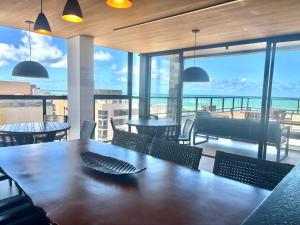 a dining room with a table and chairs and windows at UMI Flats - Intermares by Refúgio Hospedagens in Cabedelo +39 photos