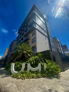 a tall building with a sign in front of it at UMI Flats - Intermares by Refúgio Hospedagens in Cabedelo
