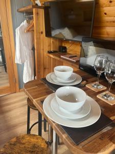 Mill House Farm Pods - Lapwing Lodge في Pilling: طاولة خشبية مع وعاءين أبيضين وكؤوس نبيذ +9 صور