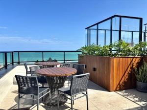 a patio with a table and chairs and the ocean at UMI Flats - Intermares by Refúgio Hospedagens in Cabedelo