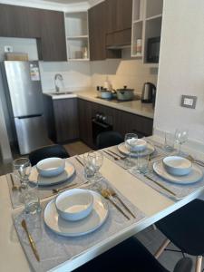 Hermoso Departamento a Pasos de la Playa - La Serena في لا سيرينا: مطبخ مع طاولة مع الأطباق وكؤوس النبيذ +10 صور