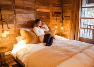 a woman sitting on a bed talking on a cell phone at Demeure Sauvage - Étage 2 in Villard-Reculas