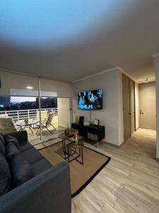 Hermoso Departamento a Pasos de la Playa - La Serena في لا سيرينا: غرفة معيشة مع أريكة وتلفزيون بشاشة مسطحة