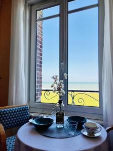 een tafel met borden en bloemen voor een raam bij Les Pieds dans l'eau appartement vue mer in Dieppe