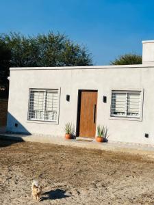 une maison blanche avec une porte marron et deux fenêtres dans l'établissement Corazón de Ayrampos APART, à Villa Dolores