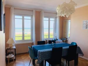 een eetkamer met een blauwe tafel en stoelen en ramen bij Les Pieds dans l'eau appartement vue mer in Dieppe +19 foto's
