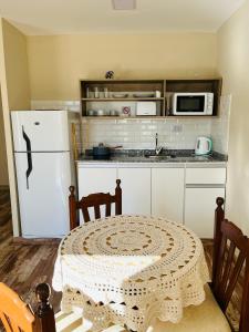 une cuisine avec une table et un réfrigérateur blanc dans l'établissement Corazón de Ayrampos APART, à Villa Dolores
