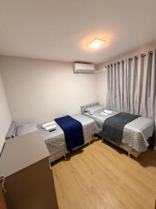 a room with two beds and a desk in it at Ponta Negra Apartment in Manaus