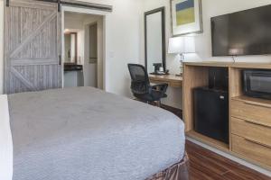 Un dormitorio con una cama y un escritorio con televisión. en Boca By The Sea Hotel, en Boca Raton