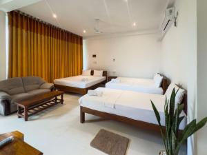 una camera d'albergo con due letti e un divano di JAMI River Side Hotel & Yala Safari Place a Tissamaharama Altre 84 foto