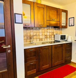 een keuken met houten kasten en een magnetron bij GuestHost - Petite Fleur - Cozy La Thuile Flat in La Thuile