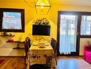 een eetkamer met een tafel en een tv bij GuestHost - Petite Fleur - Cozy La Thuile Flat in La Thuile