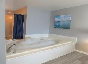 a bath tub in a bathroom with a painting on the wall at Pointes North Beachfront Hotel - 2 Person Spa Tub Studios in Traverse City