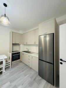 a kitchen with white cabinets and a stainless steel refrigerator at Modern 2-Bed Near Tirana and Airport with Balconies in Kamëz
