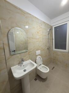 a bathroom with a sink and a toilet and a mirror at Modern 2-Bed Near Tirana and Airport with Balconies in Kamëz