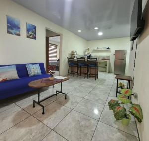 a living room with a blue couch and a kitchen at Corcovado Abi Apartments in Puerto Jiménez