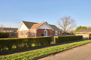 une maison en briques avec des haies devant une rue dans l'établissement Host & Stay - WillowStay, à Martham