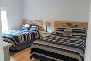 two beds with striped sheets in a bedroom at The Villa at 125 Royal Poste Rd in Sunset Beach