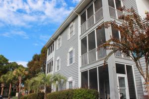 a gray building with windows and trees at The Villa at 125 Royal Poste Rd in Sunset Beach