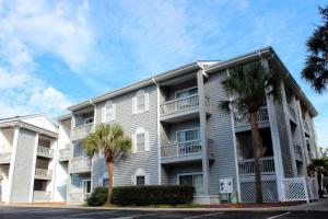 a large apartment building with palm trees in front at Beach Bungalow by Coastal Concierge in Sunset Beach