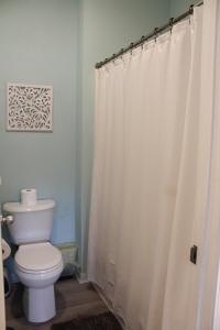 a bathroom with a toilet and a shower curtain at Beach Bungalow by Coastal Concierge in Sunset Beach