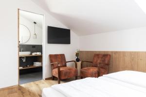 una camera da letto con due sedie, un letto e uno specchio di Garni Hotel Tauber a Bressanone