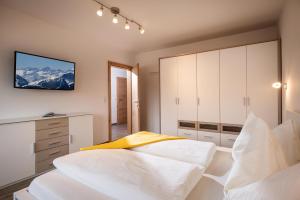 a bedroom with white furniture and a tv on the wall at Mount Apart in Zell am Ziller