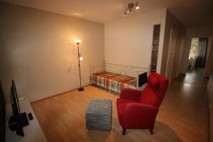 ロヴァニエミにあるHotel Aakenus Apartment Koskiのリビングルーム(赤い椅子、ベッド付)