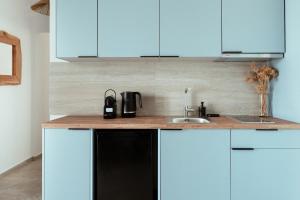 a kitchen counter with a sink and blue cabinets at Kyma Paros Apartments 2 