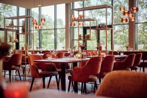 a restaurant with tables and chairs and windows at Van der Valk Hotel Sneek in Sneek