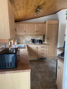 a kitchen with wooden cabinets and a counter top at Kingfisher Cosy Lakeside Lodge in Carnforth