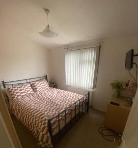 a bedroom with a bed with a checkered blanket and a window at Kingfisher Cosy Lakeside Lodge in Carnforth
