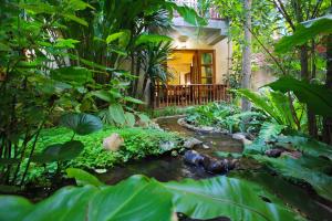 a garden with a pond and plants and a house at Shewe Wana Suite Resort in Chiang Mai