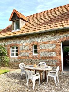 einen Tisch und Stühle vor einem Backsteingebäude in der Unterkunft CÔTE MER in Quiberville