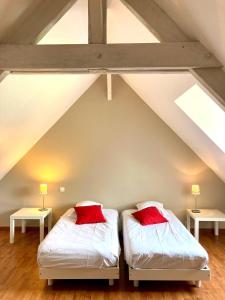 2 Betten mit roten Kissen im Dachgeschoss in der Unterkunft CÔTE MER in Quiberville