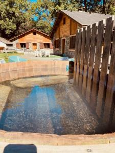 a pool with a wooden fence next to a house at Gîtes et yourte le Tucaou avec bains nordiques in Camous