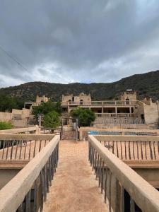 a bridge leading to a building with mountains in the background at Auberge jawahir aguerd  +78 photos