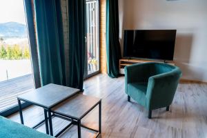 un soggiorno con sedia verde e TV di Widokowe Stodoły balia z hydromasażem na wylączność a Chyżówki