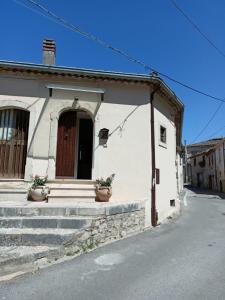 a small white house with two potted plants in front of it at Casa Canale in Gesualdo